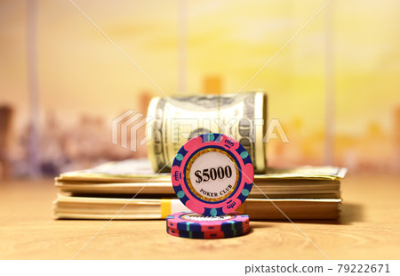 Poker chip for casino game and a bundle of one hundred dollar bills on table. Poker chip for casino game and a bundle of one hundred dollar bills on table. 79222671
