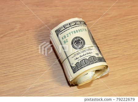 A bundle of one hundred dollar bills on table.  79222679