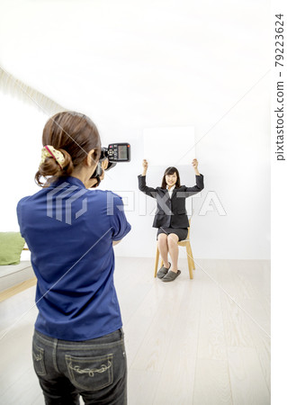 A scene of a young woman being photographed by a female photographer in the studio. 79223624