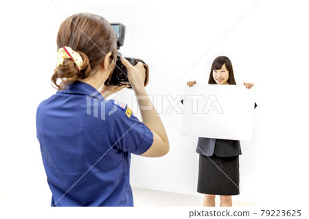 A scene of a young woman being photographed by a female photographer in the studio. 79223625