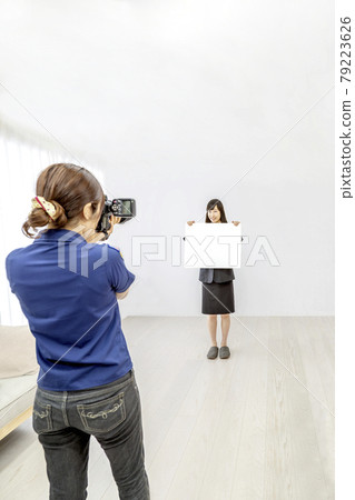 A scene of a young woman being photographed by a female photographer in the studio. 79223626