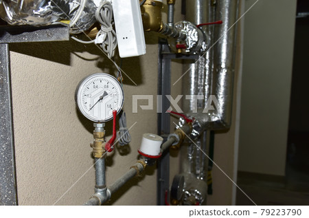Heating system in boiler room at home. Round mechanical pressure gauge for measuring pressure Heating system in boiler room at home. Round mechanical pressure gauge for measuring pressure 79223790
