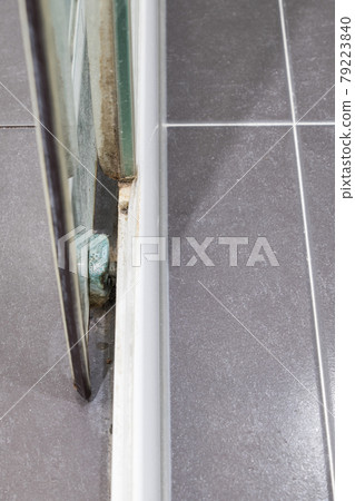 Closeup of the sliding glass door with the lichen and mold stains of the old shower enclosure. Closeup of the sliding glass door with the lichen and mold stains of the old shower enclosure. 79223840