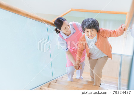 Senior women and care staff climbing stairs Senior women and care staff climbing stairs 79224487
