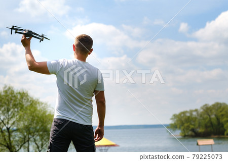 A man with a quadrocopter in his hands, raised to the sky in nature A man with a quadrocopter in his hands, raised to the sky in nature 79225073