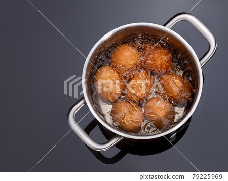 Chicken eggs are boiled in a saucepan on a glass ceramic induction hob. Cooking hard boiled eggs. 79225969