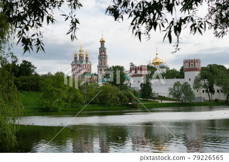 View of the Moscow Novodevichy monastery in spring evening with blurred tree leaves on the foreground View of the Moscow Novodevichy monastery in spring evening with blurred tree leaves on the foreground 79226565