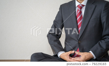 一個在工作中沉思和提神的商人。一個穿著西裝做瑜伽的男人。 一個在工作中沉思和提神的商人。一個穿著西裝做瑜伽的男人。 79229183