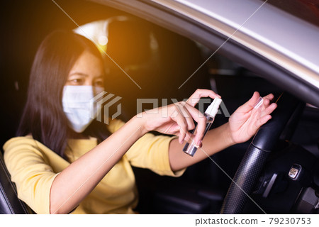 Woman using hand sanitizer spray before driving a car,Preventive measures against coronavirus,Covid-19 pandemic Woman using hand sanitizer spray before driving a car,Preventive measures against coronavirus,Covid-19 pandemic 79230753