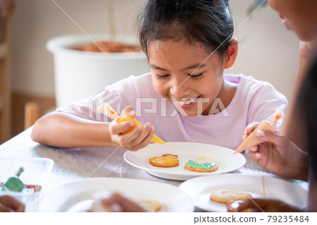 Close up asian child girl squeezing icing cream to decorate cookies with friend with fun. DIY homemade kid art and craft concept. 79235484