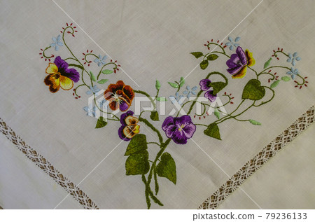 Corner with a border for embroidery of a bouquet with brown and purple pansies with small blue flowers on branches with leaves Corner with a border for embroidery of a bouquet with brown and purple pansies with small blue flowers on branches with leaves 79236133