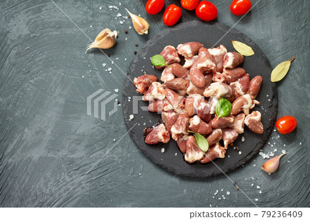 Raw livers on a slate board, cherry tomatoes and spices on a gray stone stone background. Top view with copy space. Raw livers on a slate board, cherry tomatoes and spices on a gray stone stone background. Top view with copy space. 79236409