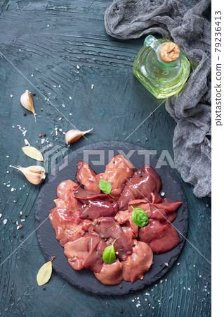 Raw chicken liver on a slate board and spices on a stone with a gray stone background. 79236413