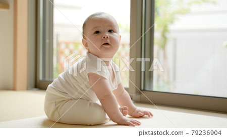 Half baby sitting by the window and looking up 79236904