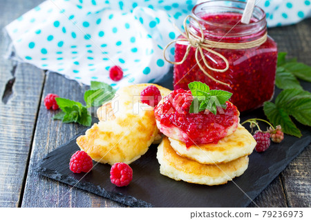 Cottage cheese fritters, pancakes with raspberry jam and fresh raspberries on a wooden rustic table. Copy space for your text. Cottage cheese fritters, pancakes with raspberry jam and fresh raspberries on a wooden rustic table. Copy space for your text. 79236973
