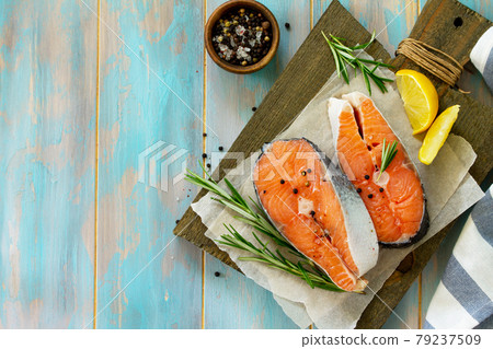 Fresh organic fish. Salmon steaks on a wooden cutting board with spices. Top view on a flat background lay. Copy space. 79237509