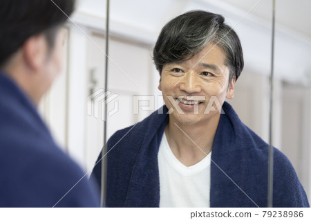 A smiling middle man looking in the bathroom mirror 79238986