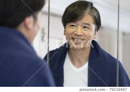 A smiling middle man looking in the bathroom mirror 79238987