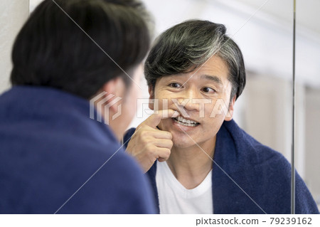 Middle-aged and older men checking their gums while looking in the mirror Middle-aged and older men checking their gums while looking in the mirror 79239162