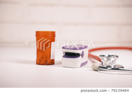 pill container, stethoscope and pulse oximeter on table pill container, stethoscope and pulse oximeter on table 79239464