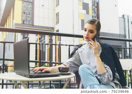Charming happy woman student communicates by phone and use laptop computer to prepare for the course work. Charming happy woman student communicates by phone and use laptop computer to prepare for the course work. 79239646