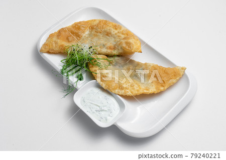 cheburek or fried dough pie with meat feeling and sauce on white background 79240221