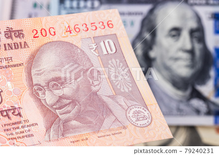 10 indian rupee with hundred dollar bill on background 79240231