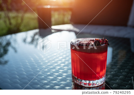 clover club cocktail drink with raspberry and rose petal outdoor at sunset 79240295