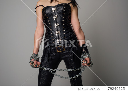 Sensual woman in black leather corset and pants with chain in hand 79240325
