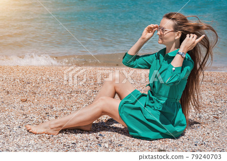 a girl with long hair in a green dress on the beach. beach holidays a girl with long hair in a green dress on the beach. beach holidays 79240703