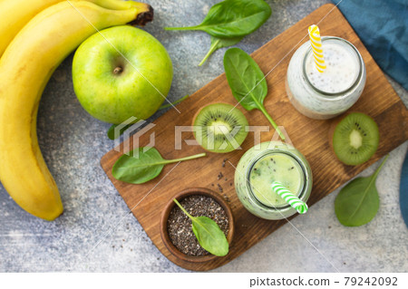 Healthy dieting and nutrition. Vegetarian concept. Blended Green detox vegetable smoothies with organic ingredients on a stone concrete tabletop. Top view flat lay background. Healthy dieting and nutrition. Vegetarian concept. Blended Green detox vegetable smoothies with organic ingredients on a stone concrete tabletop. Top view flat lay background. 79242092