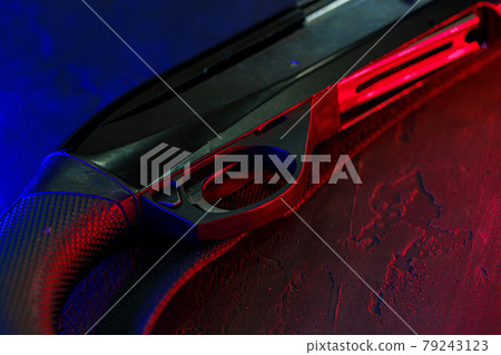 Hunting shotgun on black background with red and blue backlight 79243123