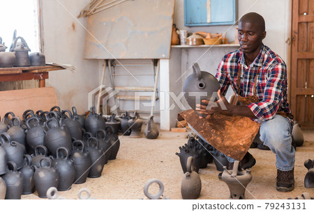 Craftsman examining handmade earthenware Craftsman examining handmade earthenware 79243131
