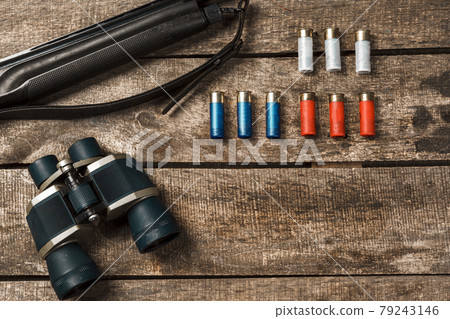 Hunting rifle and binoculars on dark wooden background Hunting rifle and binoculars on dark wooden background 79243146