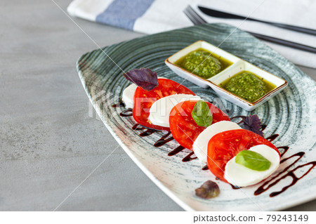 Fresh italian caprese salad with mozzarella and tomatoes on gray plate Fresh italian caprese salad with mozzarella and tomatoes on gray plate 79243149