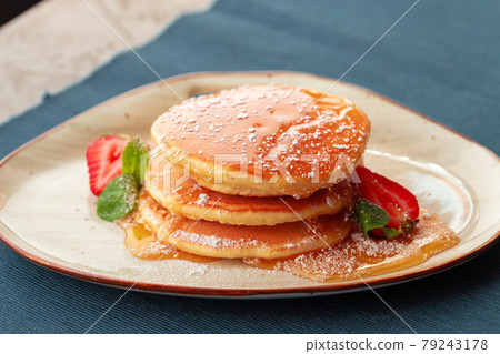 Pancakes with strawberry and maple syrup on table 79243178