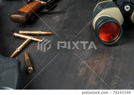 Hunting rifle and binoculars on dark wooden background Hunting rifle and binoculars on dark wooden background 79243194