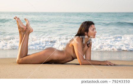 Naked girl lying on stomach on sand 79243350