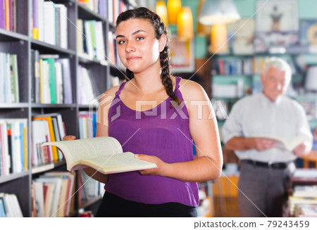Young woman is choosing interesting book 79243459