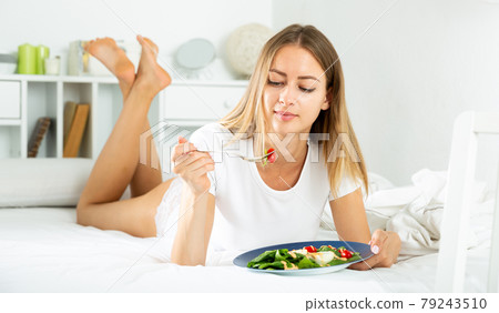Portrait of lady eating vegetable salad in bed at home alone 79243510