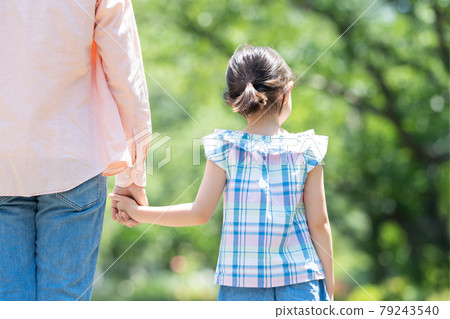 Back view of parents and children walking hand in hand Back view of parents and children walking hand in hand 79243540