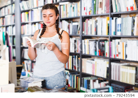 Teenage girl customer is choosing new book Teenage girl customer is choosing new book 79243594