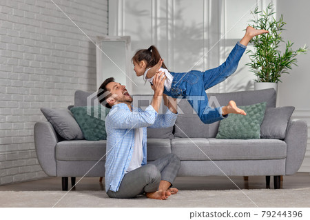 Happy little child girl flying in fathers arms 79244396