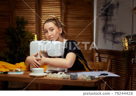 Beautiful young seamstress working on sewing machine 79244428