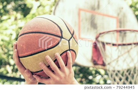 Scoring basket in basketball court. Handsome male playing basketball outdoor. Toned. Scoring basket in basketball court. Handsome male playing basketball outdoor. Toned. 79244945