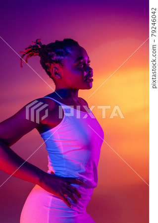 Beautiful African girl in white short summer dress posing isolated over bright colorful neon background. 79246042