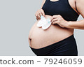 Close up of pregnant belly. Young beautiful pregnant woman standing on white background. Beautiful tender mood photo of pregnancy. 79246059
