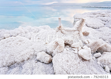 Small plastic chairs completely covered with crystalline salt on shore of dead sea, closeup detail, clear blue water near Small plastic chairs completely covered with crystalline salt on shore of dead sea, closeup detail, clear blue water near 79248313