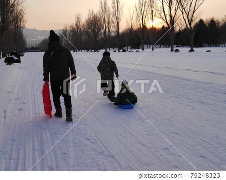 父母和孩子晚上在公園散步的背影（冬天） 79248323