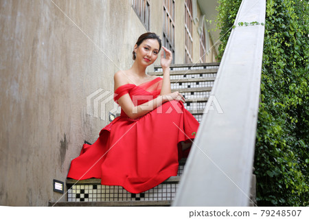 Young Asian Woman in a beautiful red dress looking at camera with smile. Fashion model, bride or pre-wedding concept. 79248507